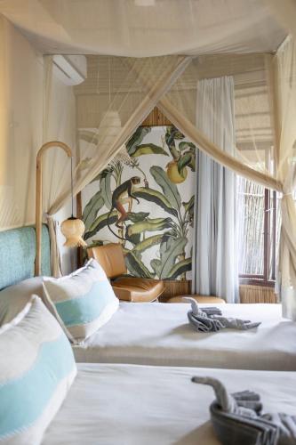 a bedroom with two beds and a wall with plants at Thonga Beach Lodge in Mabibi