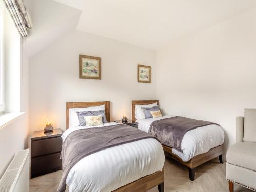 a bedroom with two beds and a chair at The Beech House in Aviemore