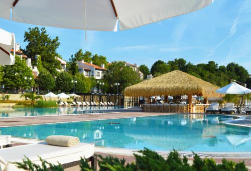 una gran piscina con sillas y una sombrilla de paja en Oasis Resort Apartment, Луксозен Апартамент в комплекс ОАЗИС, en Lozenets