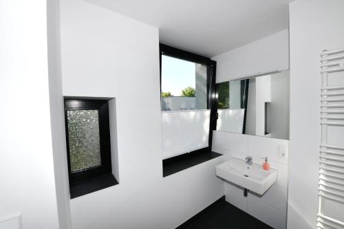 ein weißes Badezimmer mit einem Waschbecken und einem Spiegel in der Unterkunft Glück Auf Appartements Hillerstraße Köln in Köln