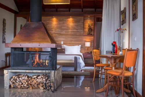 a room with a fireplace and a bed and a bedroom at Mirante da Colyna Hotel & SPA in Monte Verde