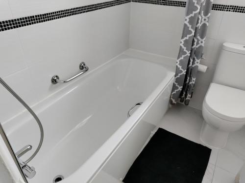 a white bathroom with a shower and a toilet at Beautiful House in Ruislip in Northwood