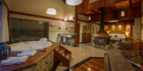 a large bathroom with a tub and a fireplace at Mirante da Colyna Hotel & SPA in Monte Verde