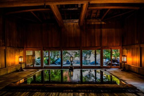 an indoor pool in a room with windows at Houshi Onsen Chojukan in Minakami