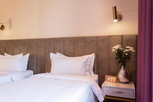 a bedroom with two beds with white sheets and flowers at Orient Hotel Bishkek in Bishkek