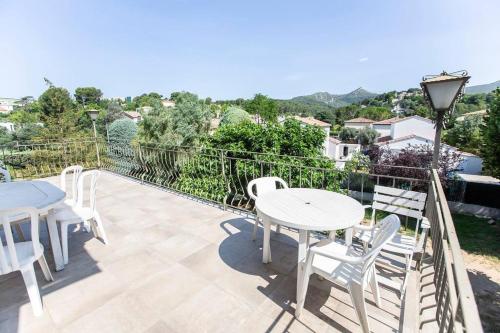 eine Terrasse mit weißen Tischen und Stühlen auf dem Balkon in der Unterkunft Havre de paix familial avec grand jardin in Marseille