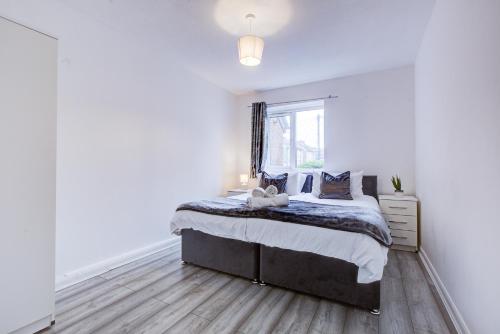 ein weißes Schlafzimmer mit einem Bett und einem Fenster in der Unterkunft Inviting Urban Apartment in Croydon in Croydon