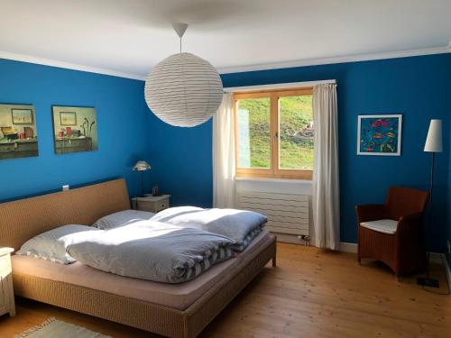 a blue bedroom with a bed and a window at Plattis 4 in Klosters