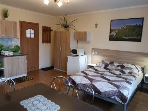 1 dormitorio con cama, mesa y cocina en Noclegi Arenda en Niedzica