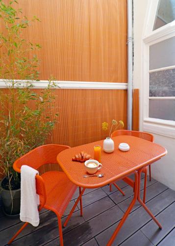 une table et des chaises orange sur la terrasse dans l'établissement Villa Adèle, Escapade Belle-Époque - Appt 01, à Mers-les-Bains