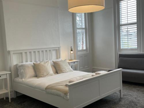 - un lit blanc dans une chambre avec un canapé et des fenêtres dans l'établissement Spacious Victorian Birkdale Apartment with Garden, à Southport
