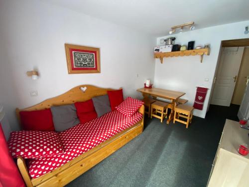 um quarto com uma cama de madeira com almofadas vermelhas e uma mesa em Appartement 4 personnes em Risoul