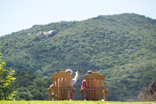 two children sitting in chairs looking at a mountain at Mirante da Colyna Hotel & SPA in Monte Verde