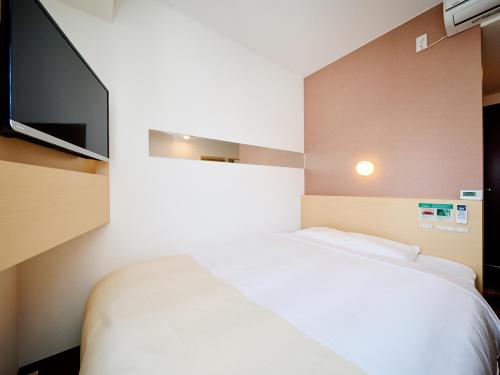 a bedroom with a bed and a flat screen tv at Super Hotel Akihabara Suehirocho in Tokyo