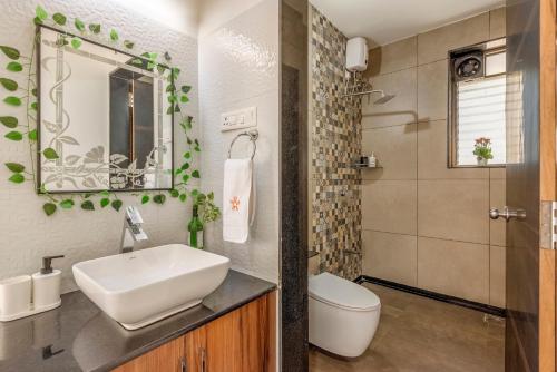 a bathroom with a sink and a toilet and a mirror at SaffronStays Lakeview Nivara - Farm Stay Villa with Private Pool near Pune in Pune