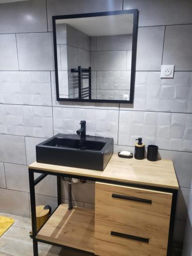 une salle de bain avec un lavabo noir et un miroir dans l'établissement COSY, à Coubron