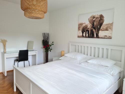 a white bedroom with a bed and a picture of elephants at 2 BR - Kingsize Bett - Garten - Parken - Küche in Zürich