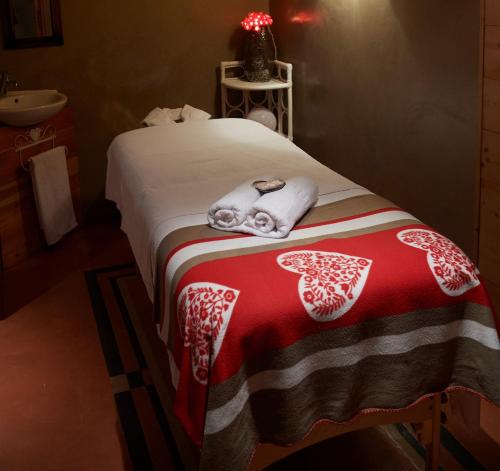 a bedroom with a bed with towels and a sink at Logis Hôtel et Spa Le Christiania in La Salle Les Alpes