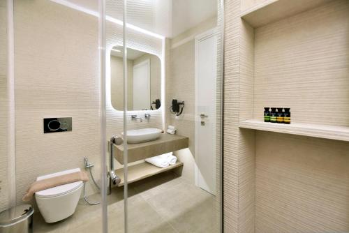 a bathroom with a sink and a toilet and a mirror at Anais Milos Suites in Adamas