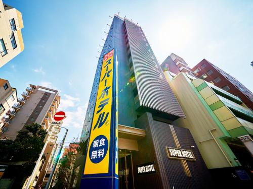 a tall building with a sign in a city at Super Hotel Akihabara Suehirocho in Tokyo