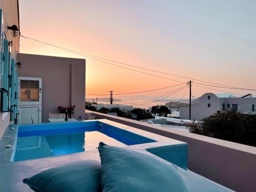 a swimming pool on the side of a house with the sunset at Flora's House & Cave Winery in Pirgos