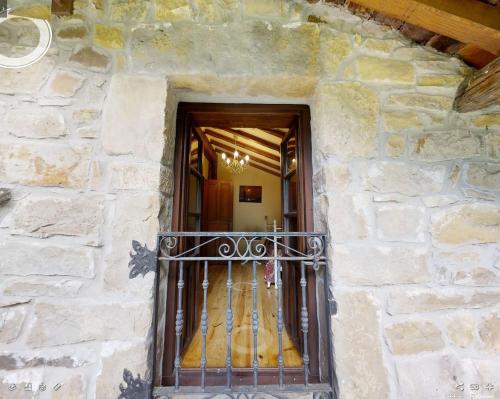 un edificio de piedra con balcón frente a una puerta en Cabaña Pasiega "La Reina del Paraíso", en San Roque de Ríomiera