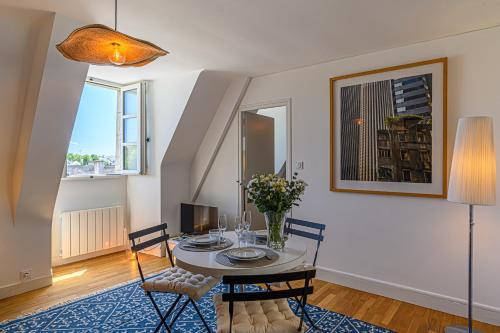 une salle à manger avec une table et des chaises et deux fenêtres dans l'établissement Au coeur des Remparts - Bel appt coeur de Vannes, à Vannes