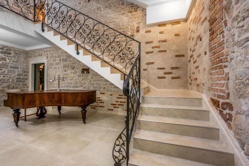 a staircase with a piano next to a brick wall at Sizgoric Palace Suites Sibenik in Šibenik