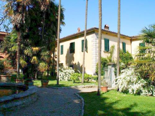 uma casa grande com palmeiras num quintal em Cosy Farmhouse in Bacchereto with Swimming Pool em Carmignano