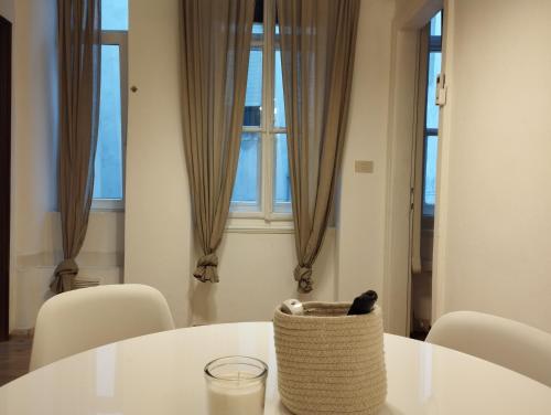 een witte tafel met stoelen en een mand erop bij DormiTrieste City Life Apartment in Trieste