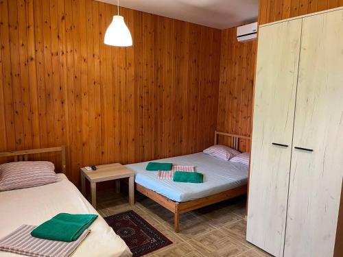 two beds in a room with wooden walls at Гостевой дом "MARUS" in Tsandrypsh