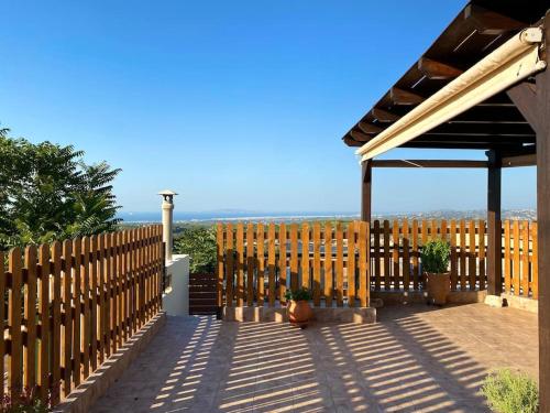 a wooden fence with a pergola on a patio at Serenity Stone House, a Blissful Retreat in Petrokefalo
