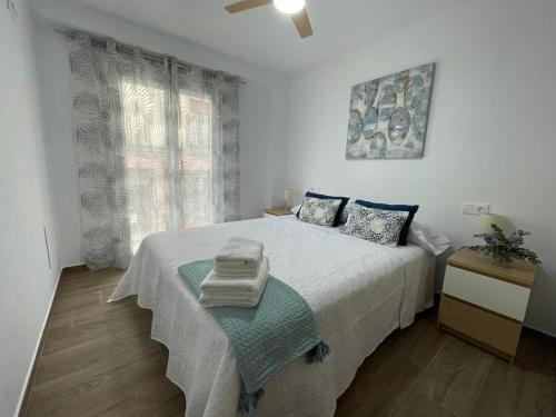 a white bedroom with a bed and a window at Apartamento del Agua in Rute