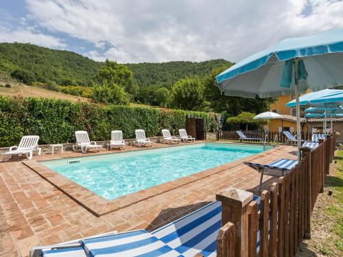 アッシジにあるHoliday Home in Assisi with Poolのスイミングプール(椅子、パラソル付)