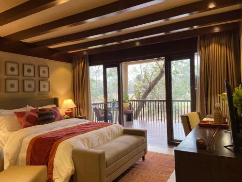 a bedroom with a large bed and a balcony at Miraaya Wellness and Golf Resort in Chitwan