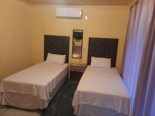 Habitación con 2 camas y espejo. en Maboe Leisure Resort, en Rustenburg