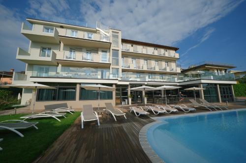 un hôtel avec une piscine, des chaises et un bâtiment dans l'établissement Hotel Palazzo del Garda & Spa, à Desenzano del Garda