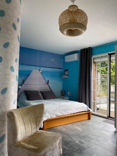 a blue bedroom with a bed and a chair at Le Lagon in Jargeau