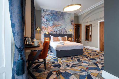 ein Schlafzimmer mit einem Bett, einem Schreibtisch und einem Gemälde in der Unterkunft Keavan's Port Hotel, Dublin in Dublin