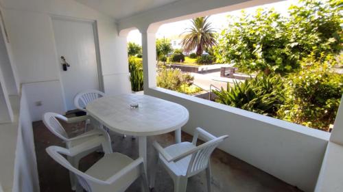 uma pequena mesa branca e cadeiras numa varanda em Bettencourt House em Santa Cruz da Graciosa
