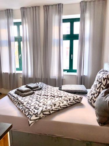 a bed with a blanket on it in a room with windows at Studioapartment M15 im Plagwitzer Szeneviertel in Leipzig