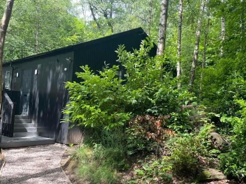 a black house in the woods with trees at Inglewood House and Spa in Alloa