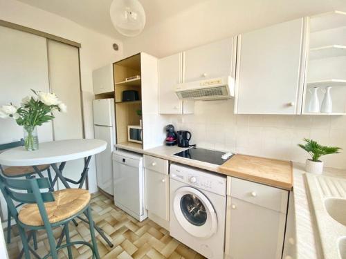 - une cuisine avec des placards blancs, une table et un lave-linge dans l'établissement Studio à 100 m de la plage avec clim et balcon, à Nice