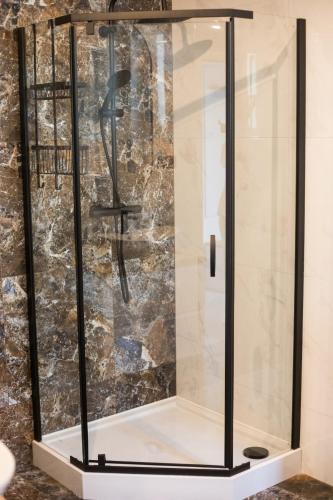 a shower with a glass enclosure in a bathroom at Apartament Miętowy Rumianek in Lwówek