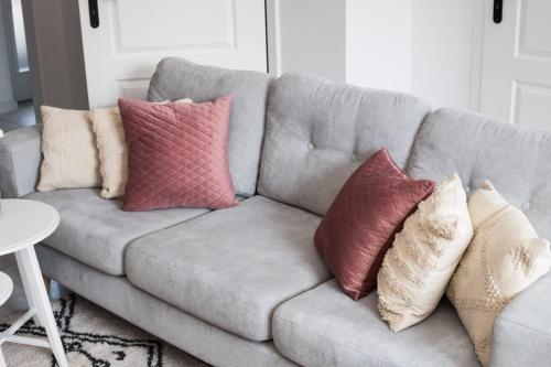 a gray couch with pillows on it in a living room at Apartament Miętowy Rumianek in Lwówek