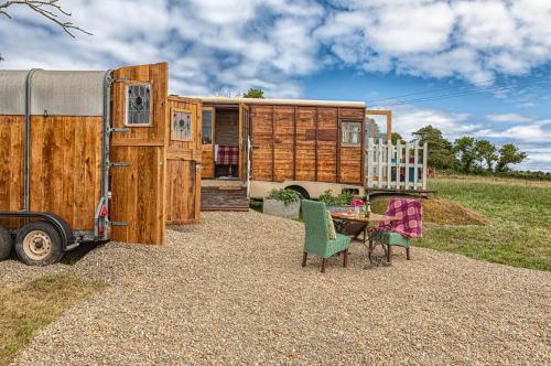 a tiny house with a table and chairs next to a trailer at Dennis in Goodwick