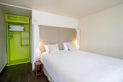 - une chambre avec un grand lit blanc et un placard vert dans l'établissement Campanile Reims Sud Bezannes, à Reims