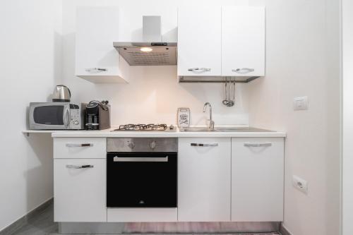 a kitchen with white cabinets and a black oven at Casa Andrea in Assemini