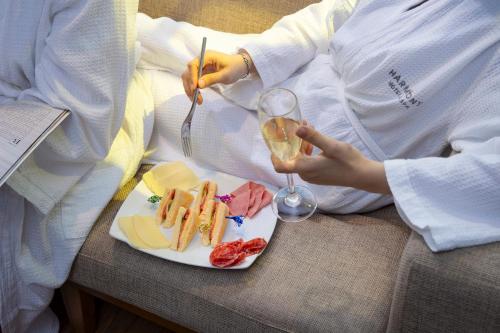 a person with a plate of food and a glass of wine at Harmony Saigon Hotel & Spa in Ho Chi Minh City