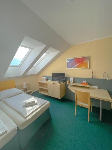 a room with two beds and a desk and a table at Slunečný Penzion in Tasovice
